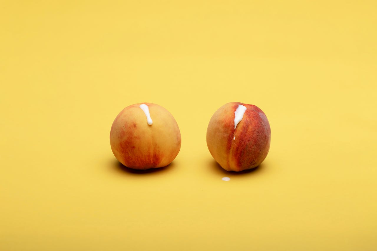hero-img-01 Studio shot of two fresh peaches with cream on a bright yellow background, offering vibrant colors and copy space.